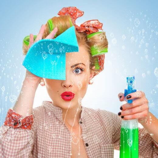 Woman with curlers cleaning a window with spray and cloth.