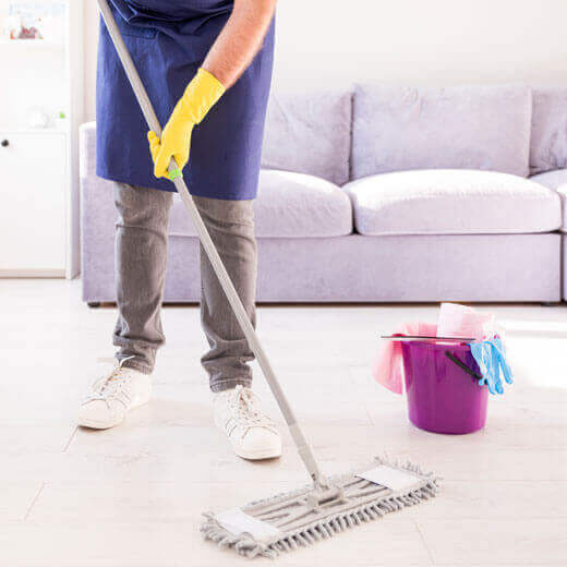 Person mopping the floor in a clean living room.
