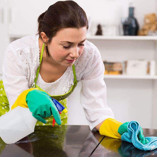Woman cleaning a glass surface with gloves and cloth.